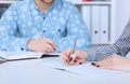 Business woman making notes at office workplace with male colleague at the background. Just hands over the table Royalty Free Stock Photo