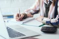 Business woman making notes with silver pen in office background. Business finance savings loan and credit concept.