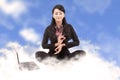 Business woman meditating above the clouds