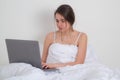 Business woman on morning. Woman watching laptop. Beautiful young woman using laptop on bed at home. Lazy freelancer Royalty Free Stock Photo