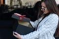 Business woman opens gift. Brunette girl holding gift box. Girl holding a beautiful gift box in her hands