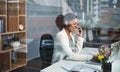 Business woman on a phone call sitting at a desk typing an email on a office computer. Smiling corporate female talking Royalty Free Stock Photo