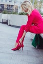 Business woman in pink suit suffering from legs pain due to high heeled shoes, uncomfortable shoes Royalty Free Stock Photo