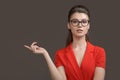 Business woman pointing up at camera over gray background. Young stylish woman with glasses