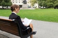 Business woman reads while sitting on park bench