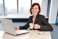 Business woman with red hair at work smiling on laptop computer desk and drinking coffee Royalty Free Stock Photo