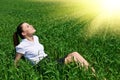 Business woman relaxing in green grass field outdoor under sun. Beautiful young girl dressed in suit resting, spring landscape, br Royalty Free Stock Photo