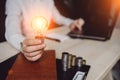 Business woman`s hand holding light bulb with using notebook and notebook and money stack. Idea saving energy and accounting Royalty Free Stock Photo