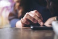 A business woman`s hand touching and sliding finger on a black smart phone on wooden table Royalty Free Stock Photo