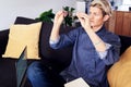 Business woman with short hair looks into glasses, using laptop at modern apartment.