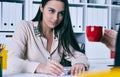 Young business woman showing growth graphic and taking to her female colleague who drinks coffee in an office interior. Royalty Free Stock Photo