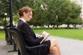 Business woman sits on parks bench and writes in her journal Royalty Free Stock Photo