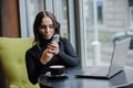 A business woman sits at a table by the window and takes pictures on her phone. blogger girl Royalty Free Stock Photo