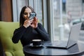 A business woman sits at a table by the window and takes pictures on her phone. blogger girl Royalty Free Stock Photo