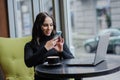 A business woman sits at a table by the window and takes pictures on her phone. blogger girl Royalty Free Stock Photo