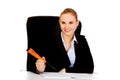 Business woman sitting behind the desk and writes something with big pen Royalty Free Stock Photo