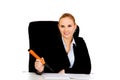 Business woman sitting behind the desk and writes something with big pen Royalty Free Stock Photo