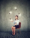 Business woman sitting on a chair playing with light bulbs