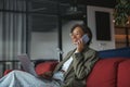 a business woman is sitting on a couch using a laptop and talking on a cell phone in nice modern coworking office Royalty Free Stock Photo