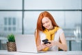 Business woman sitting in office, looking at graphics and uses smartphone Royalty Free Stock Photo