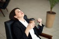 Business woman sitting relaxed on a chair leaning back with closed eyes during coffee break Royalty Free Stock Photo