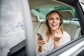 Business woman with smartphone and headphones sitting on back seats in taxi car. Royalty Free Stock Photo