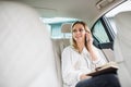 Business woman with smartphone and laptop sitting on back seats in taxi car. Royalty Free Stock Photo