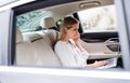 Business woman with smartphone and laptop sitting on back seats in taxi car. Royalty Free Stock Photo