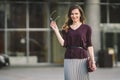 Business woman standing on street against office building. City business woman working. Portrait business woman smiling