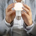 Business woman in a suit holds a turned-on electric lamp in her hands in close-up Royalty Free Stock Photo