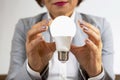 Business woman in a suit holds a turned-on electric lamp in her hands in close-up