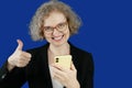 Business woman in suit using mobile phone on blue chromakey background, small business entrepreneur looking at her mobile phone