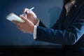 Business woman taking notes in paper on dark blue background