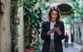 Business woman talking on mobile phone outdoors, professional woman in suit walking on old city street checks her smartphone Royalty Free Stock Photo