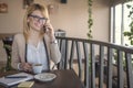 Business woman talking on smartphone and taking a notes, in a coffee shop, restaurant Royalty Free Stock Photo