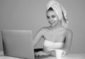 Business woman with towel on head facial cream on face hold cup of coffee working on laptop. Morning beauty. Portrait of Royalty Free Stock Photo