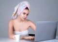 Business woman with towel on head facial cream on face hold cup of coffee working on laptop. Morning beauty. Portrait of Royalty Free Stock Photo