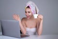 Business woman with towel on head facial cream on face hold cup of coffee working on laptop. Morning beauty. Portrait of