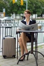 Business woman with travel suitcase reads newspaper at cafe Royalty Free Stock Photo