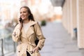 Business woman in trench coat talks on her mobile phone outdorrs