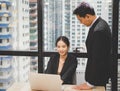 Business woman typing on laptop. Boss standing near employee and controlling process