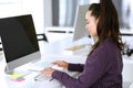 Business woman using computer at workplace in modern office. Brunette secretary or female lawyer smiling and looks happy Royalty Free Stock Photo