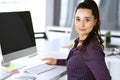 Business woman using computer at workplace in modern office. Brunette secretary or female lawyer smiling and looks happy Royalty Free Stock Photo