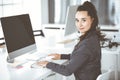 Business woman using computer at workplace in modern office. Brunette secretary or female lawyer smiling and looks happy Royalty Free Stock Photo