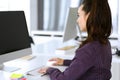 Business woman using computer at workplace in modern office. Brunette secretary or female lawyer smiling and looks happy Royalty Free Stock Photo