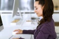 Business woman using computer at workplace in modern office. Brunette secretary or female lawyer smiling and looks happy Royalty Free Stock Photo