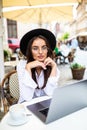 Business woman using laptop at cafe. Young beautiful woman sitting in a coffee shop and working on computer Royalty Free Stock Photo