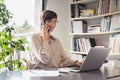 Business woman using laptop and talking on phone Royalty Free Stock Photo