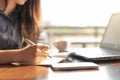 Business woman using laptop and writing on a notepad with a pen at a coffee shop. Working on project concept Royalty Free Stock Photo