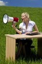 Business Woman Using Megaphone In A Green Field